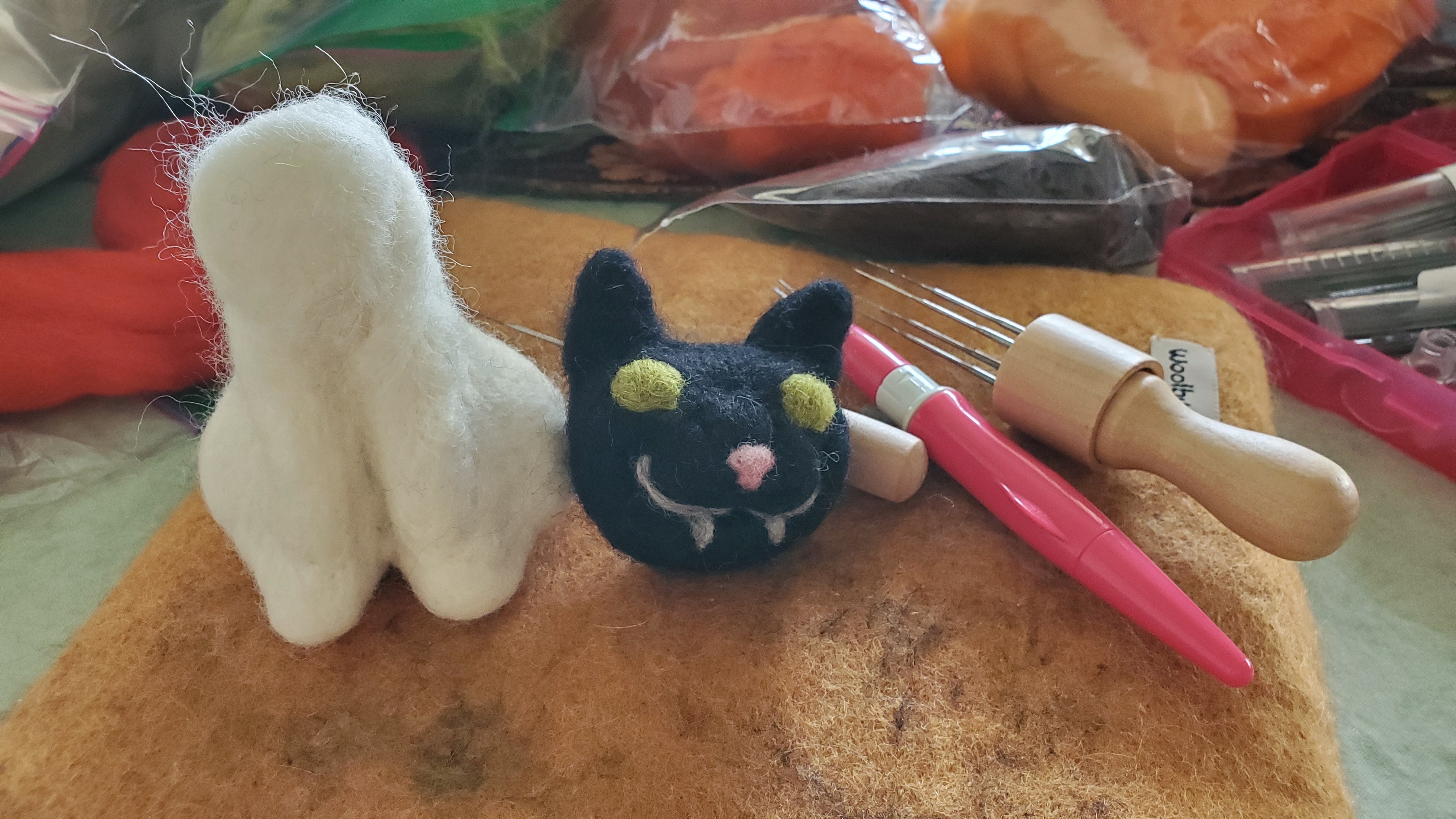 cream core wool body of cat with black cat head sitting beside