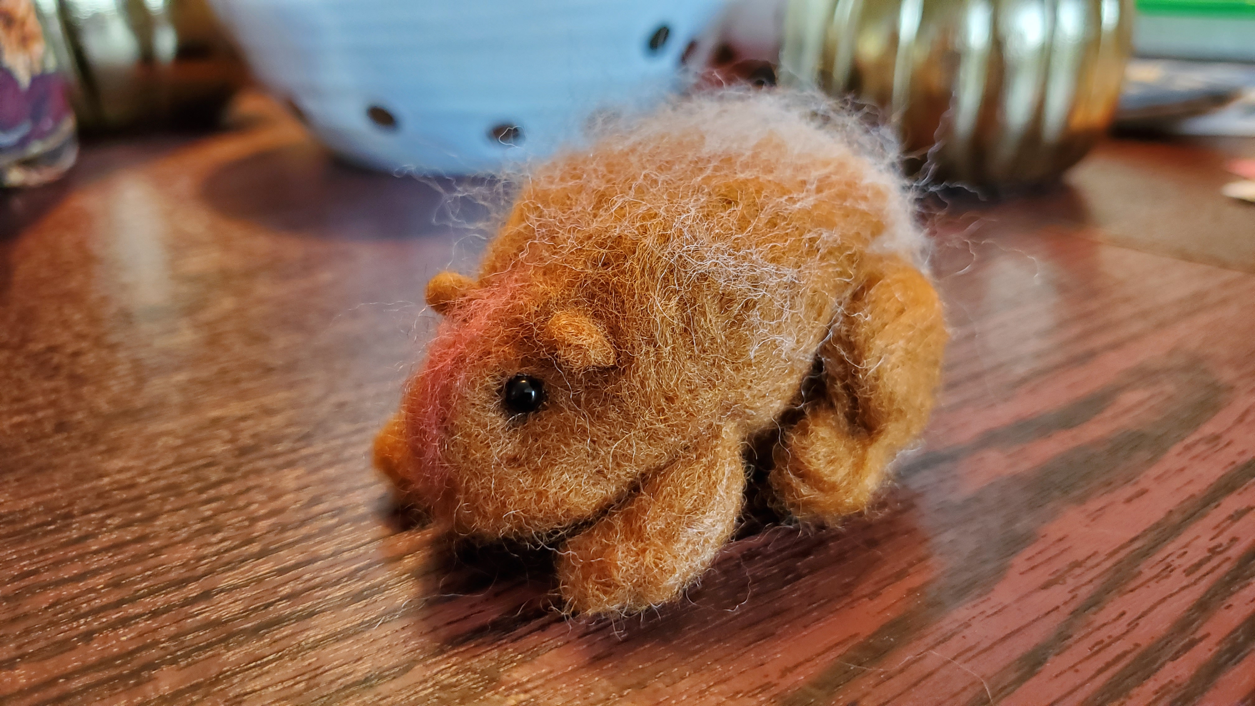 little felt porcupine with black bead eyes sitting on a table